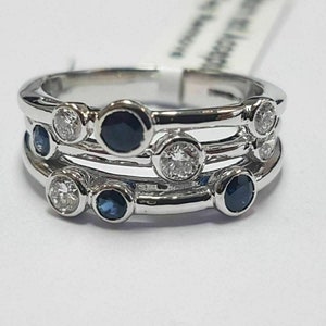 Puede incluir: Un anillo de plata con tres bandas engastadas con zafiros azules y diamantes transparentes alternados.