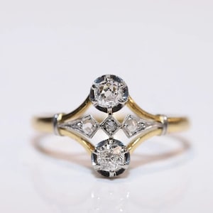 Könnte beinhalten: Ein zarter Goldring mit Diamantenbesatz. Der Ring hat einen zentralen Diamanten, der von kleineren Diamanten in einem geometrischen Muster umgeben ist.