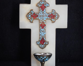 May include: A white cross with an ornate, multi-colored cross design in the center. The cross has a small, decorative bowl at the bottom. The cross design features red and blue accents.