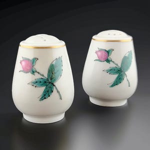 May include: A set of two white ceramic salt and pepper shakers with a gold trim and a floral design featuring pink roses and green leaves.
