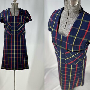 May include: A blue plaid dress with red and yellow stripes. The dress has a square neckline and short sleeves. It has two patch pockets on the front.