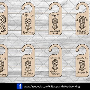 Op de afbeelding: Set van tien houten deurhangers met ananasontwerpen en verschillende zinnen, waaronder "Stoor gerust", "Probeer het, je zou het kunnen leuk vinden", "Klop niet voordat je het hebt geprobeerd", "Kom binnen", "Officiële leden", "Het feest is hier", "Hulp nodig bij groepstherapie", "Bedankt voor het langskomen", "Ga je gang, klop".