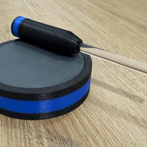 May include: A gray sharpening stone with a black and blue trim, and a black handle with a wooden blade. The sharpening stone is round and the handle is resting on top of it.