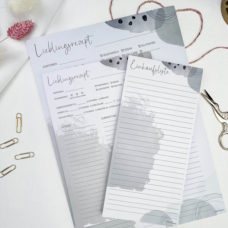 May include: Two gray recipe cards with a gray and white abstract design. The top card has the text "Lieblingsrezept" and the bottom card has the text "Einkaufsliste".