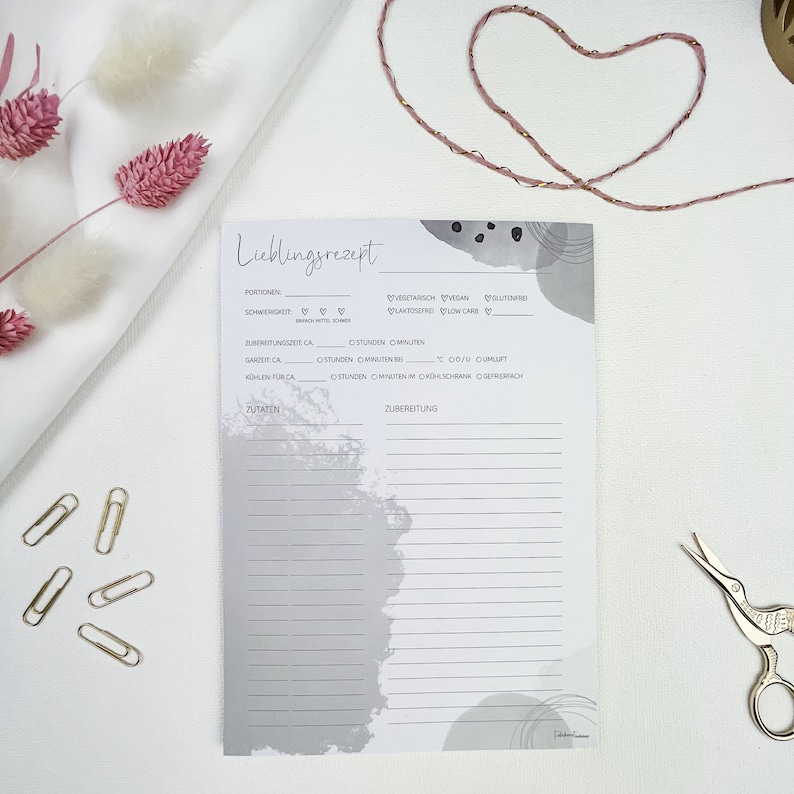 May include: A white recipe card with gray abstract watercolor designs. The card has sections for recipe name, servings, difficulty, preparation time, cook time, cool time, ingredients, and instructions. The card also has checkboxes for vegetarian, vegan, gluten-free, lactose-free, and low-carb.