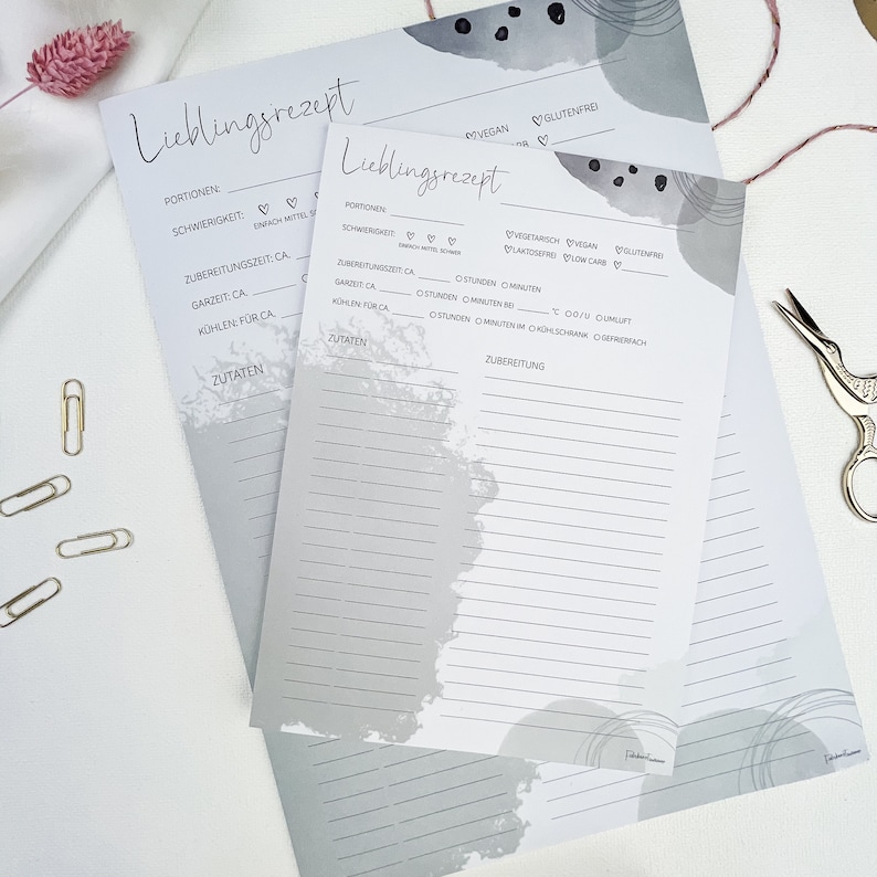 May include: Two gray printable recipe cards with a gray watercolor background. The cards have headings for "Lieblingsrezept" (German for "favorite recipe"), "Portionen" (portions), "Schwierigkeit" (difficulty), "Zubereitungzeit" (preparation time), "Garzeit" (cooking time), "K&uuml;hlen f&uuml;r" (cool for), and "Zutaten" (ingredients).
