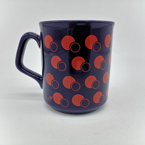 May include: A purple ceramic mug with a pattern of overlapping red and black circles.