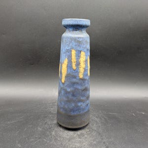 May include: A blue ceramic vase with yellow accents. The vase has a textured surface and a rounded shape.