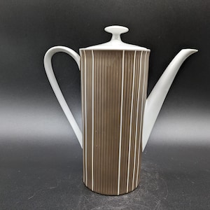 May include: A white ceramic coffee pot with a brown striped design. The pot has a lid with a knob on top and a spout on the side.