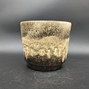 Könnte beinhalten: Ein brauner und weißer Keramiktopf mit einem gesprenkelten Überzug. Der Topf hat eine abgerundete Form und eine breite Öffnung.