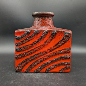 Könnte beinhalten: Rote und schwarze Keramikvase mit strukturierter Oberfläche und geometrischem Muster.