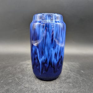 Puede incluir: Una taza de cerámica blanca con un asa negra y el texto "But First, Coffee" en negro, con una fuente de estilo manuscrito. La taza está sobre una superficie blanca.