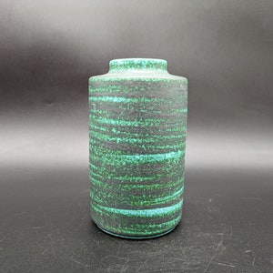 May include: A green and black ceramic vase with a striped pattern. The vase is cylindrical in shape and has a smooth, matte finish.