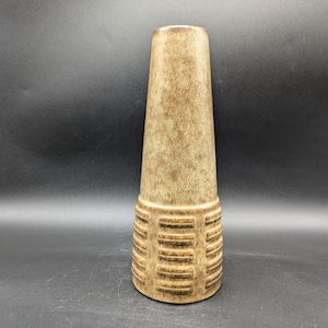 Könnte beinhalten: Eine braune Keramikvase mit einem geometrischen Muster um die Basis.