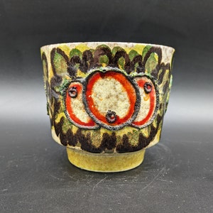 May include: A ceramic planter with a green, black, and red floral design. The planter has a rounded base and a wide, open top.