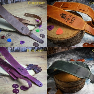 May include: Four leather guitar straps in different colors: chestnut, cognac, burgundy, and green. Each strap has a different name engraved on it: KD, NSD, IM, and CHIVES.