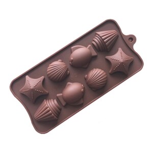 May include: Brown silicone mould with eight cavities shaped like seashells, starfish, and fish.