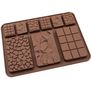 May include: A brown silicone chocolate mould with various designs. The mould features rectangular and square shapes with patterns including hearts, cracked textures, and grid lines. The mould is designed for making homemade chocolates.