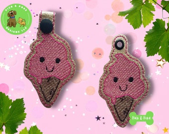 Può includere: Due portachiavi a forma di cono gelato rosa con facce sorridenti e finiture glitterate dorate. I coni gelato hanno basi a cono marroni e sono ricamati con la scritta "Pick & Poke Designs LLC".