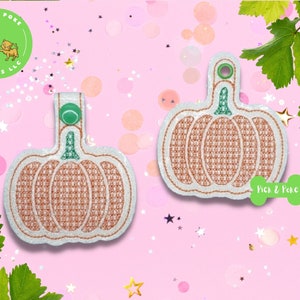 May include: Two orange pumpkin-shaped keychains with green stems and a white background. The keychains have a white and orange checkered pattern. The text "Pick & Poke" is on the bottom right keychain.