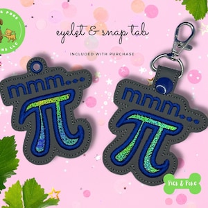 May include: Two gray Pi symbol keychains with blue and green embroidery. One keychain has a silver clasp. The text "mmm..." is embroidered above the Pi symbol. The phrase "eyelet & snap tab" is above the keychains.