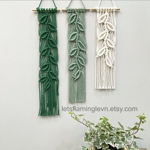 May include: Three macrame wall hangings with a leaf design. The hangings are in shades of green and white. The hangings are attached to wooden dowels.