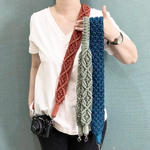 Puede incluir: Tres correas de cámara hechas de macramé con diferentes colores y patrones. Las correas son marrón, verde y azul. Las correas están colgadas del hombro de una persona.