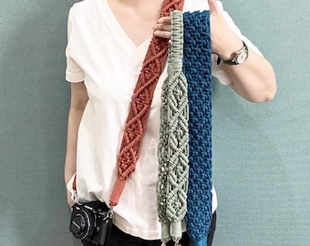 May include: Three camera straps made of macrame with different colors and patterns. The straps are brown, green, and blue. The straps are hanging from a person's shoulder.