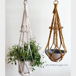 May include: Two macrame plant hangers, one white and one mustard yellow, with a plant in the white hanger and a blue ceramic pot in the yellow hanger. The text "Lets Flamingle VN" is visible at the bottom of the image.