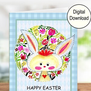 A printable greeting card with an adorable hand-painted bunny on the inside. The message says Happy Easter.  The card has a blue checked. This pic shows the card on a shelf.