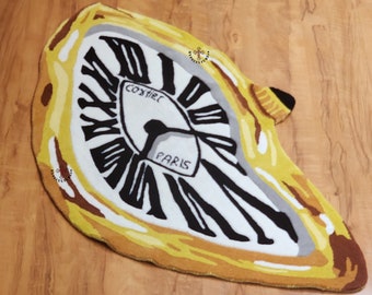May include: A yellow and white rug with a melting clock design. The clock face has black Roman numerals and the words "COXSIRE" and "PARIS" printed on it.