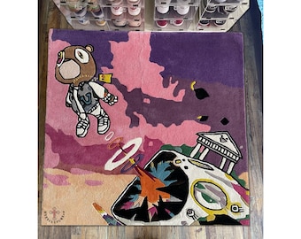 May include: A pink and purple rug with a cartoon bear wearing a jacket and a spaceship with a building on top. The rug has the text "HYPCULTUR" on it.