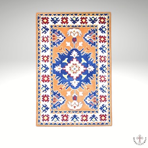 May include: A traditional rug with a geometric pattern in shades of blue, red, white, and orange. The rug has a central medallion with a starburst design and a border with repeating floral motifs.
