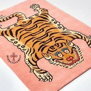 K&ouml;nnte beinhalten: Ein rosa Teppich mit einem Tigerdesign. Der Tiger liegt auf dem R&uuml;cken mit seinen Pfoten in der Luft. Der Teppich tr&auml;gt den Text "Hypecultureco" in der linken unteren Ecke.