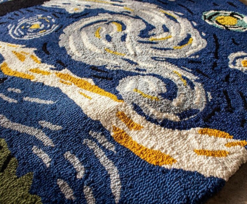 May include: A close-up of a blue, white, and yellow rug with a swirling pattern reminiscent of a famous painting. The rug is made of a soft, textured material.