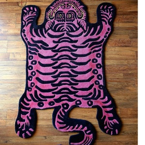May include: A pink and black tiger rug with a detailed design. The rug is made of a soft, plush material and has a unique, whimsical style.