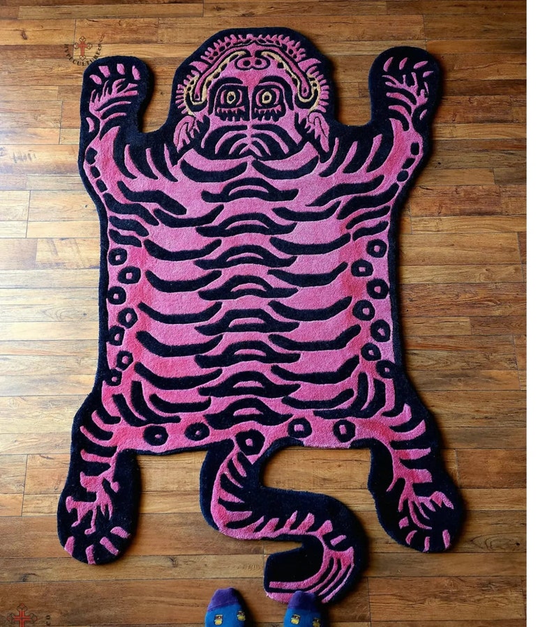 May include: A pink and black tiger rug with a detailed design. The rug is made of a soft, plush material and has a unique, whimsical style.