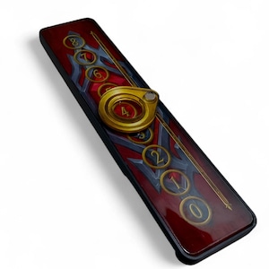 Pode incluir: Uma capa de telefone retangular com um design vermelho e cinza. A capa apresenta um anel dourado e números de 0 a 8. A borda da capa é preta.