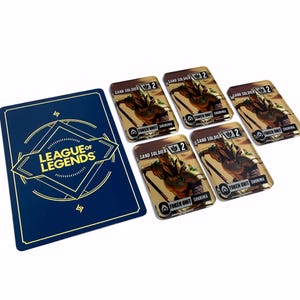 May include: A collection of League of Legends game cards. One blue card with gold text and logo, and five rectangular cards featuring a sand soldier illustration. The cards are on a white surface.