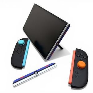 May include: A black video game console screen with a stand, two controllers, and a rail. The controllers are black with blue and orange accents. The rail has a white base with blue and red stripes.
