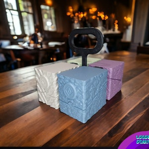 May include: Four small, square boxes with textured surfaces. The boxes are in different colors: white, light blue, green, and purple. The boxes are stacked on top of each other, with a black handle on top.