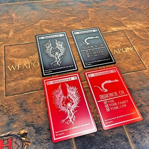 May include: Four playing cards with a black and white dragon design. The cards are labeled "Dishonored" and "Dishonor On". The text on the cards reads "You, Your Family, Your Cow".