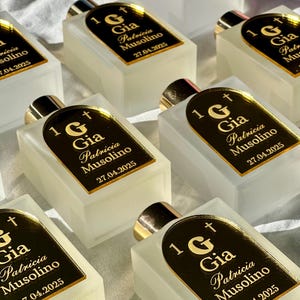 May include: A collection of small, rectangular perfume bottles with gold detailing and black labels. The labels read "1 G Gia Patricia Musolino 27.04.2025". The bottles are displayed on a white surface.