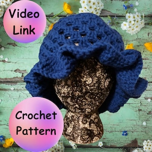 May include: A blue crocheted hat with a lacy design. The hat is on a mannequin head with a floral background.