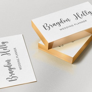 May include: White business cards with gold edges, featuring the name "Braydon Helly" and the title "Wedding Planner" in elegant script. One card is separate, while others are stacked.