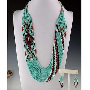 Puede incluir: Un collar largo y superpuesto de cuentas turquesa, rojo, blanco y negro con pendientes a juego. Los pendientes son de estilo colgante.