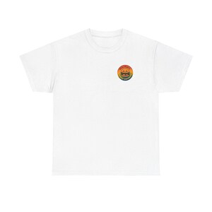 Puede incluir: Camiseta blanca con un pequeño gráfico circular colorido en el pecho. El gráfico presenta un diseño de hamburguesa con el texto "Mini Macs Family Day Home" en un círculo de colores del arcoíris. La camiseta está hecha de un material suave y cómodo.