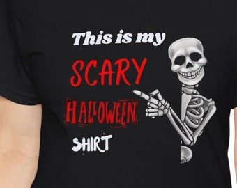 Puede incluir: Camiseta negra con un gráfico de esqueleto blanco que apunta al texto "This is my scary Halloween shirt" en rojo.