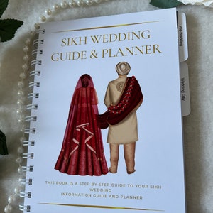 May include: A white spiral bound guide and planner for Sikh weddings. The cover features a cartoon illustration of a couple in traditional wedding attire. The title "Sikh Wedding Guide & Planner" is printed in gold lettering. The book is divided into sections for pre-wedding and wedding day.