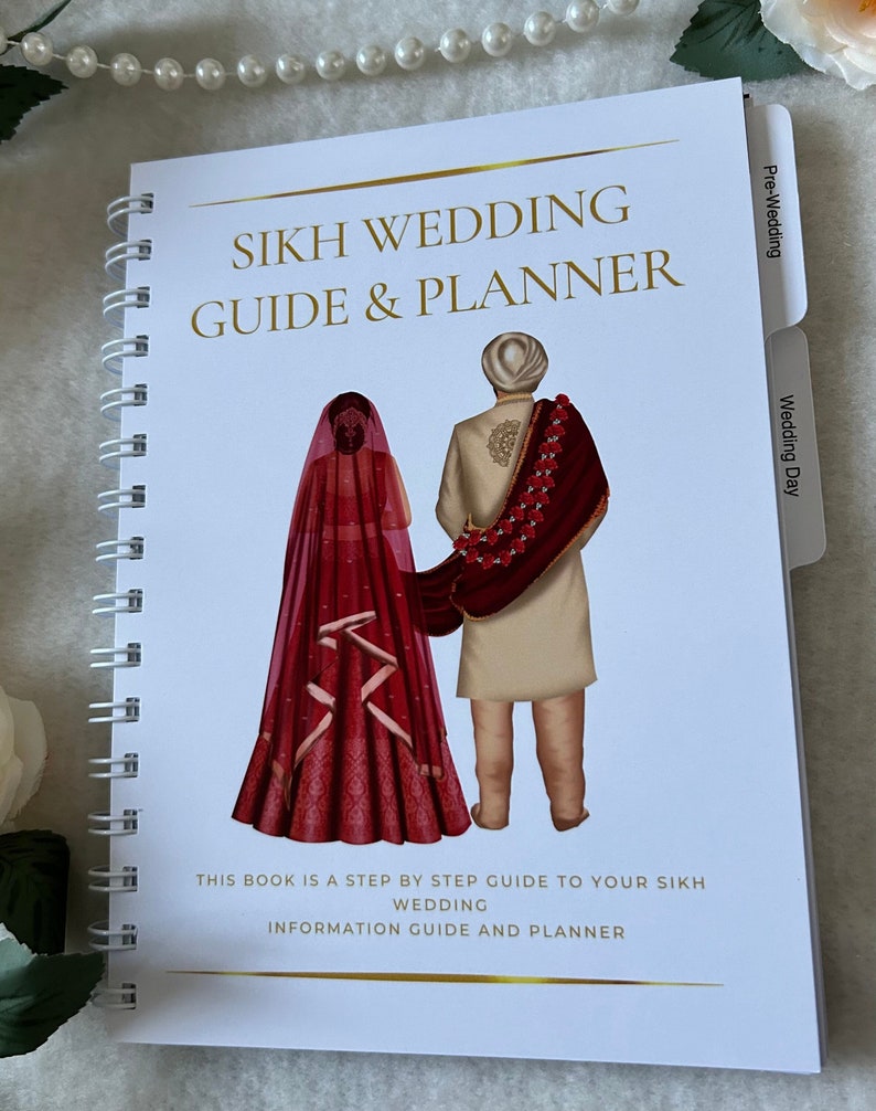 May include: A white guide and planner for Sikh weddings. The cover features a couple in traditional wedding attire, with the bride wearing a red and gold dress and the groom wearing a white turban and a maroon shawl. The text on the cover reads "Sikh Wedding Guide & Planner".